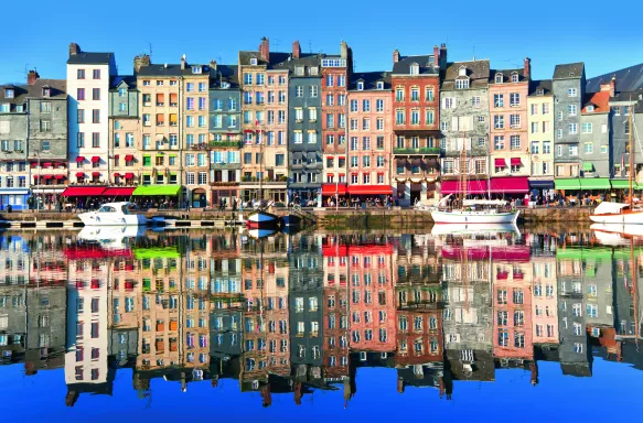 High, narrow, timber-frame houses of all colours which overlook The Port of Honfluer, a harbour located in the Norman town of Honfleur, France