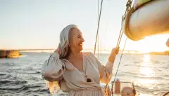 Senior woman adjusting her hair and enjoying sunset on private yacht