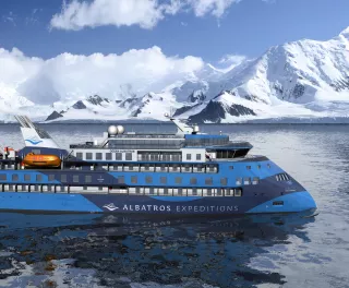 Exterior of the Ocean Albatros ship with snowy mountains in background