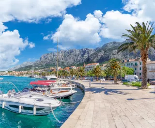 Makarska harbor under a blue cloudy sky, surrounded by the Croatia mountain range