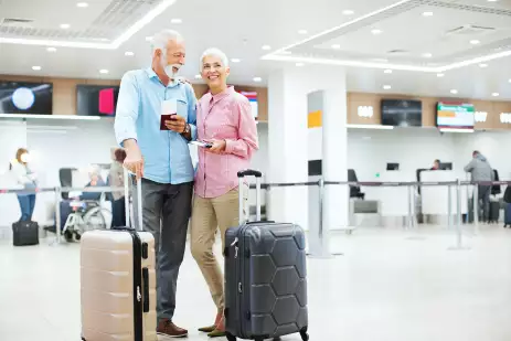 Cheerful senior couple looking at arrival departure board at an airport