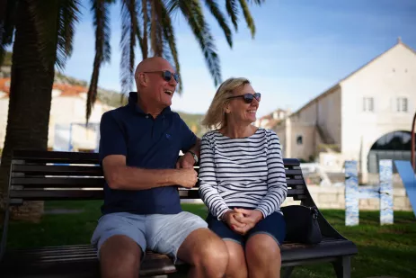 Happy mature couple sitting on a bench abroad